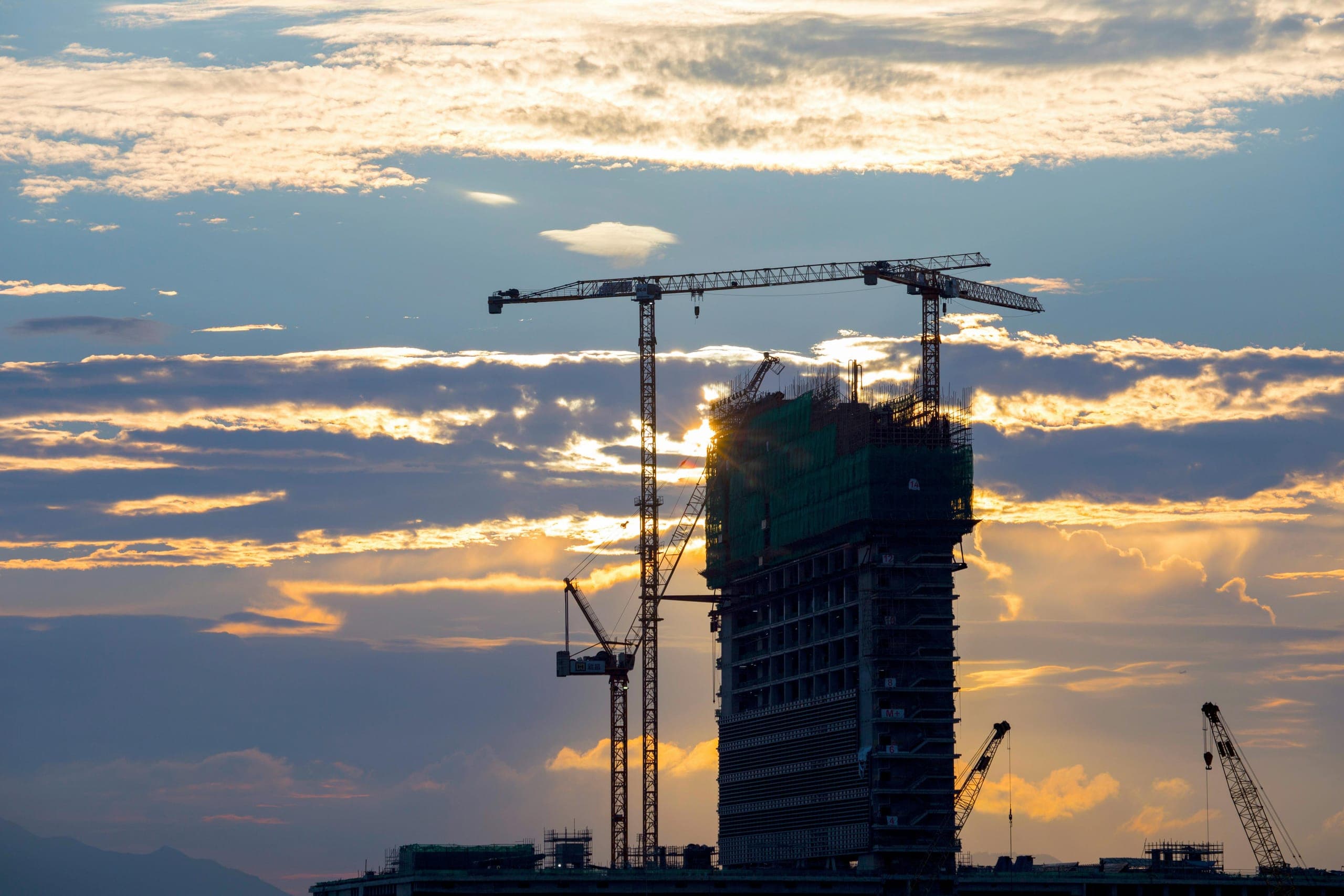 Construction site with cranes against dramatic sky